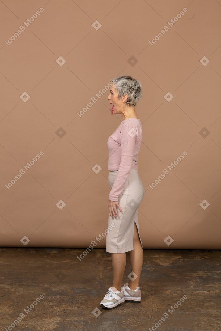 Вид сбоку женщины в повседневной одежде, показывающей язык