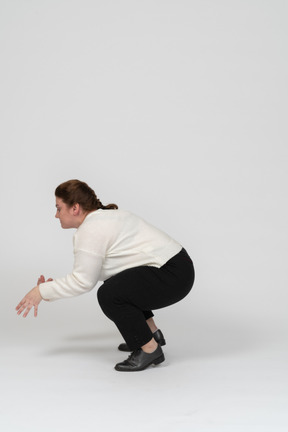 Side view of a plump woman in casual clothes squatting