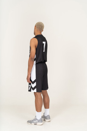Three-quarter back view of a tired young male basketball player tilting head