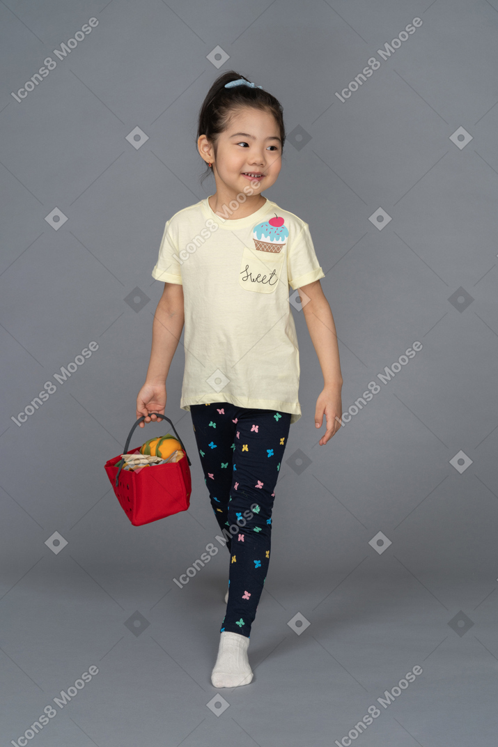 Маленькая девочка идет за продуктами с корзиной