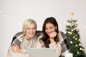 Zwei junge frauen, die lustige geschichten auf laptop lesen