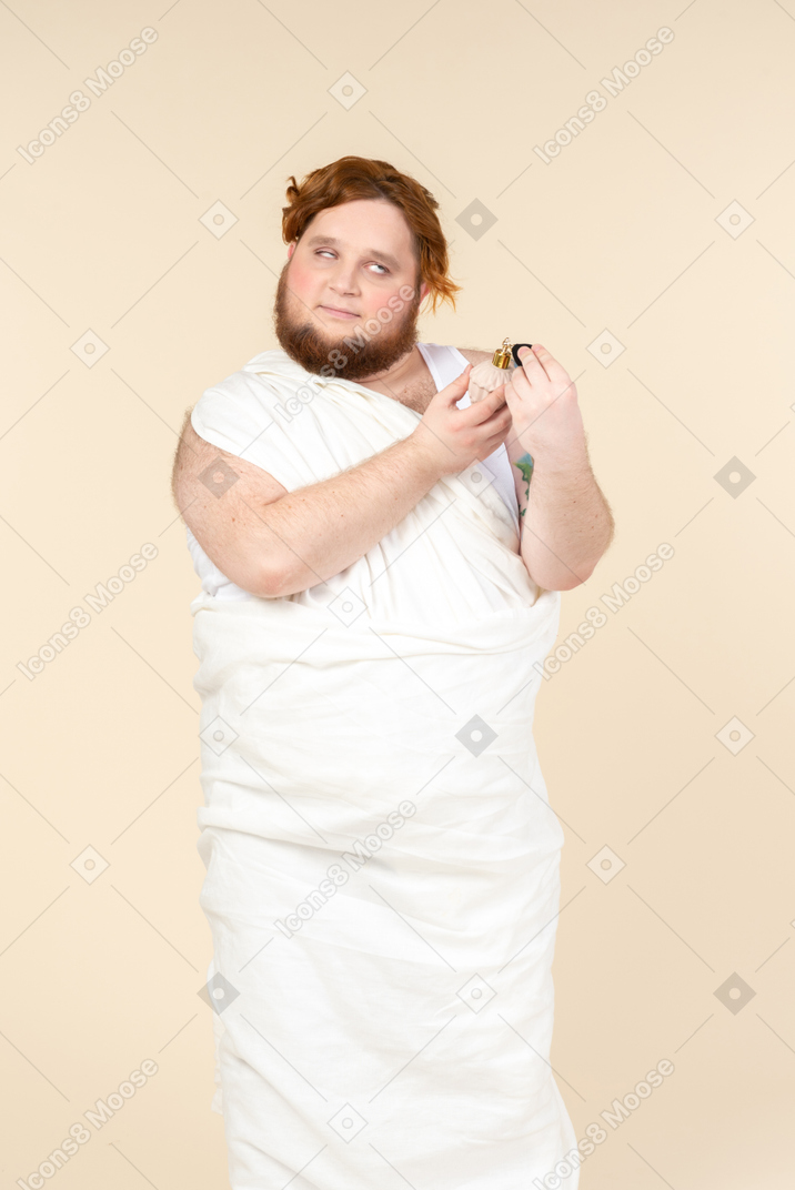 Big guy wrapped in towel applying perfume