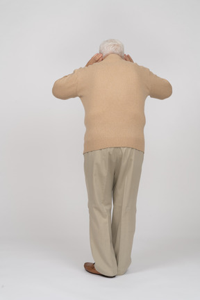 Rear view of an old man in casual clothes listening attentively