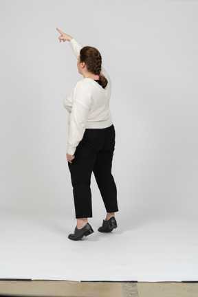 Vista posteriore di una donna grassoccia in abiti casual in piedi con il braccio alzato