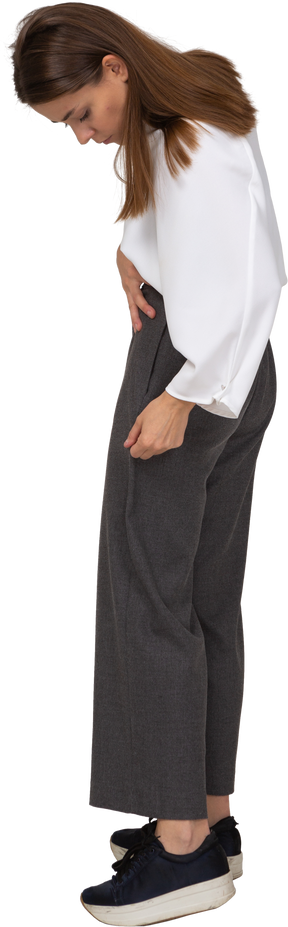 Vista laterale di una giovane donna in abiti da ufficio che si aggiusta i pantaloni
