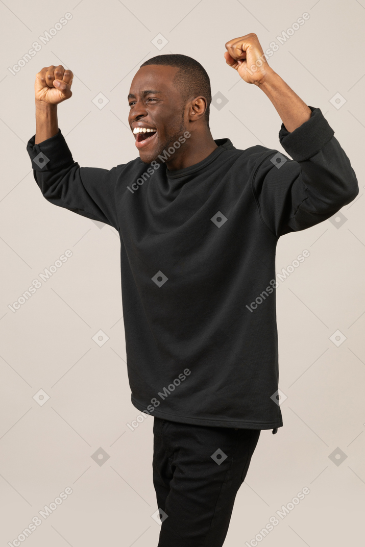 Happy young man celebrating success with hands up