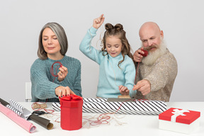 Abuelos y nieta envolviendo regalos