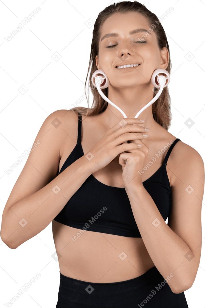 Front view of a smiling young woman massaging her face with a face roller