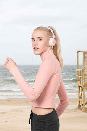 A woman with headphones on running on a beach
