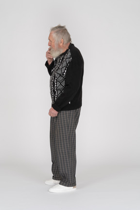Side view of a thinking elderly man holding his hand on his chin