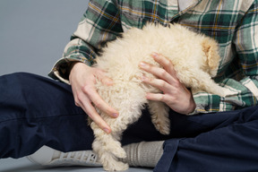 Close-up of a master in a checked shirt holding a tiny white puppy