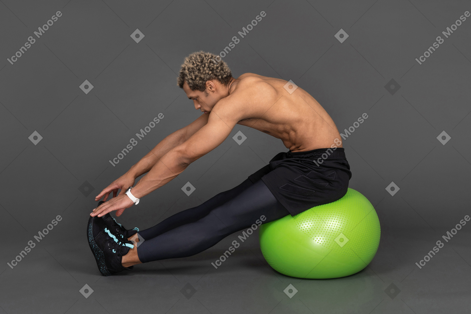 녹색 체육관 공에 앉아있는 동안 스트레칭 벗은 아프리카 남자의 측면보기