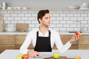 A man in an apron is holding apples