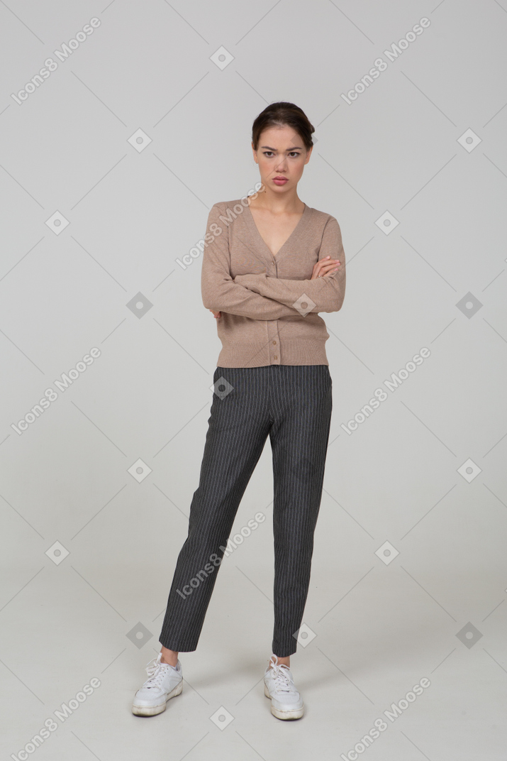 Front view of an offended young lady in pullover and pants crossing hands