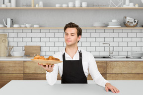 A man holding a plate of food in a kitchen