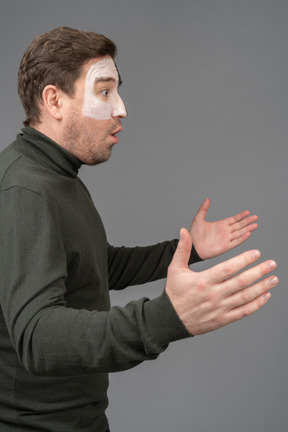 Side view of an astonished male football fan raising hands