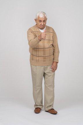 Front view of a happy old man in casual clothes showing thumb up