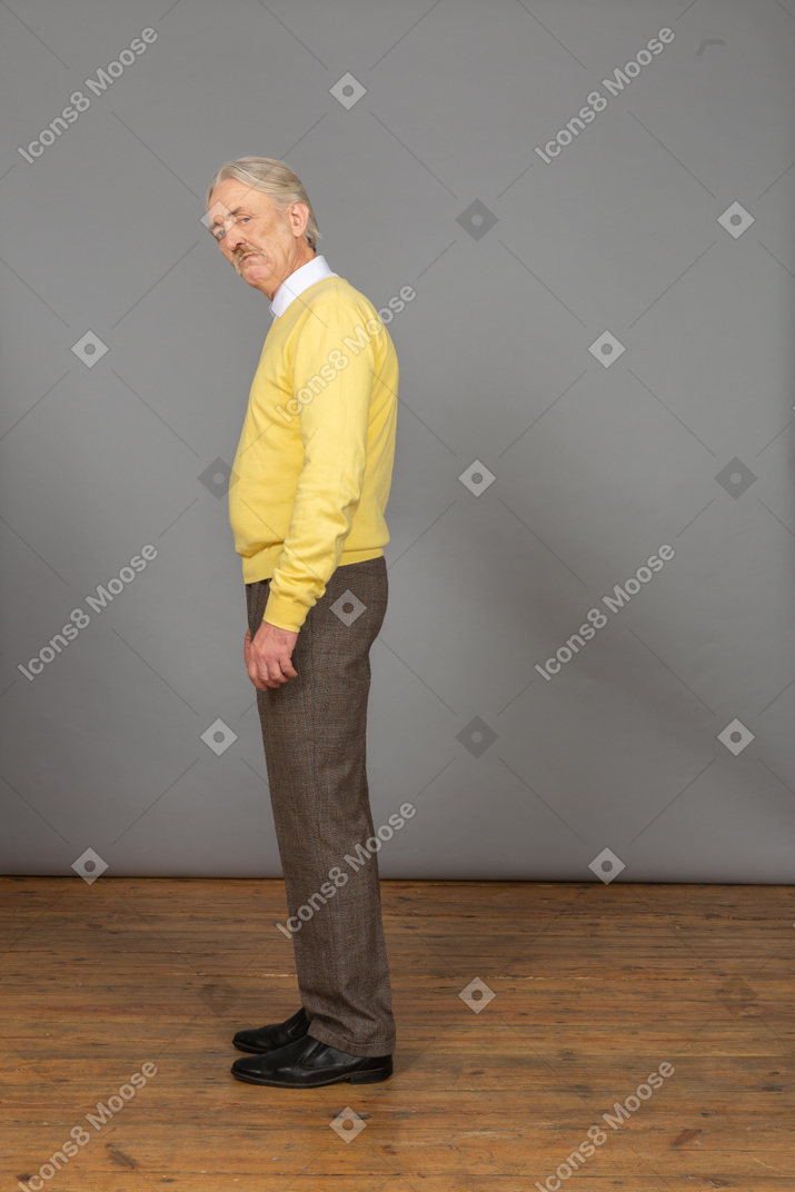 카메라를보고 노란색 스웨터에 의심스러운 노인의 측면보기