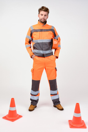 Male road worker standing in hands in his pockets