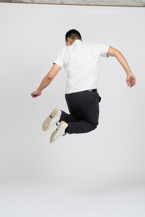 Rear view of a man in casual clothes jumping high