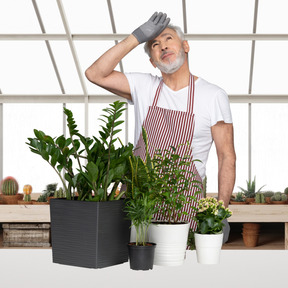 A man in an apron standing next to potted plants