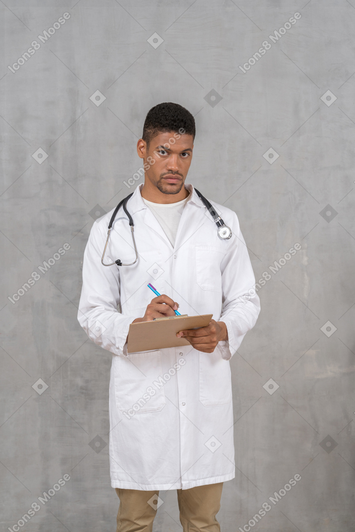 Молодой врач-мужчина ведет медицинские записи