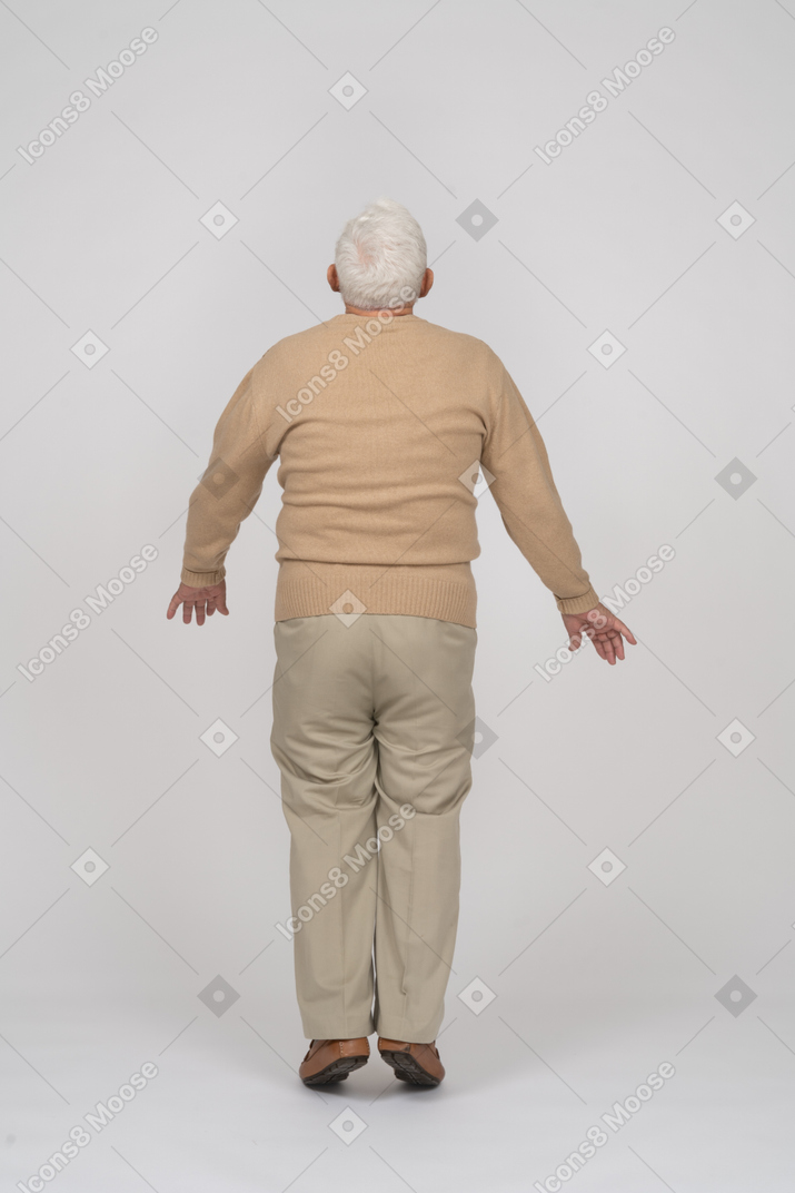 Rear view of an old man in casual clothes jumping
