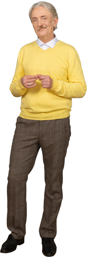 Vorderansicht ein alter lächelnder mann, der gelben pullover trägt und hände zusammenstellt und kamera betrachtet