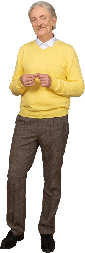 Front view an old smiling man wearing yellow pullover and putting hands together and looking at camera