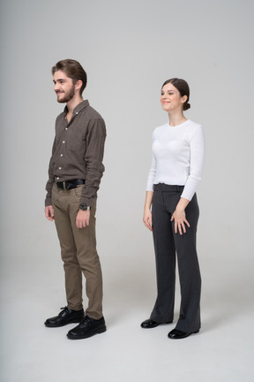 Vista de tres cuartos de una joven pareja complacida en ropa de oficina