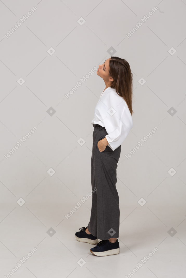 Vista lateral de una joven en ropa de oficina poniendo las manos en los bolsillos