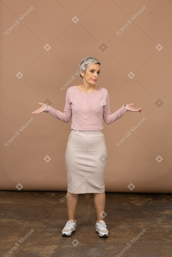 伸ばした腕で立っているカジュアルな服を着た感情的な女性の正面図