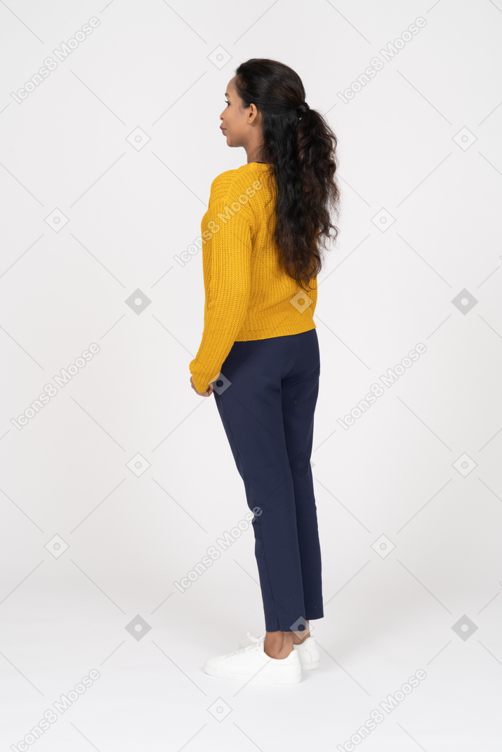 Side view of a girl in casual clothes standing with hand in pocket and pouting lips