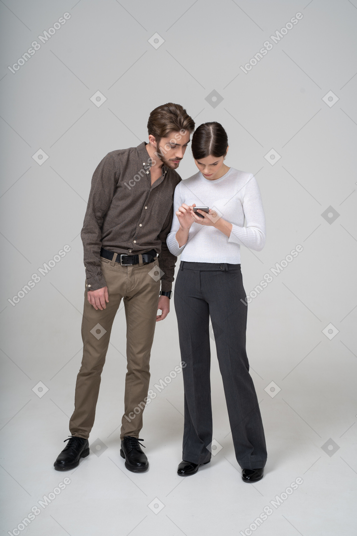 Front view of a young man peeping in her girlfriend's phone