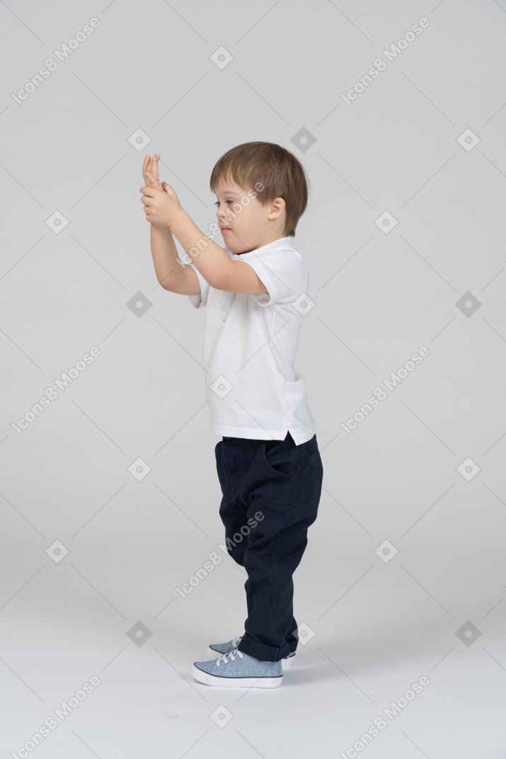 A boy standing in front of a wall with his hands