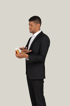 African american male in suit holding pills bottle