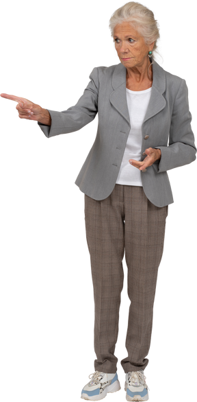 Front view of an old lady in suit pointing with finger