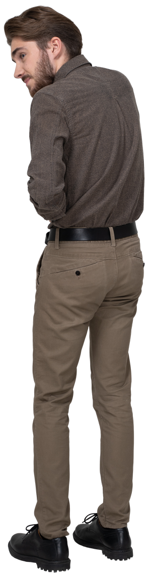 Three-quarter back view of a young man in office clothing touching stomach