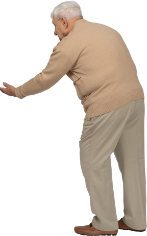 Side view of an old man in casual clothes standing with outstretched arm