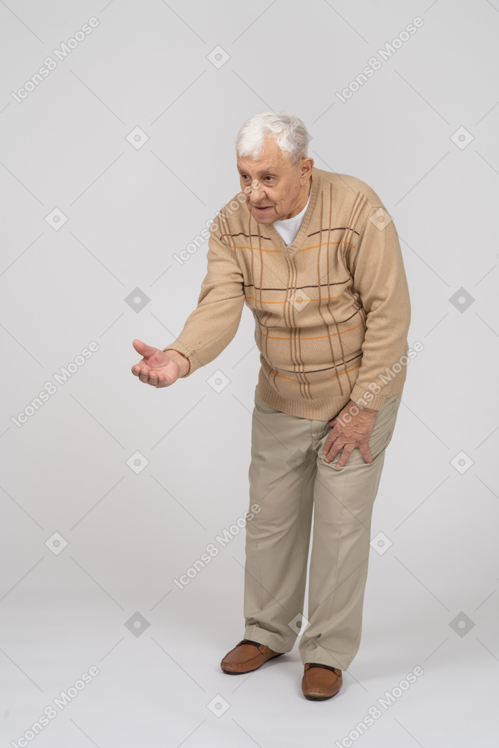 Front view of an old man in casual clothes making welcoming gesture