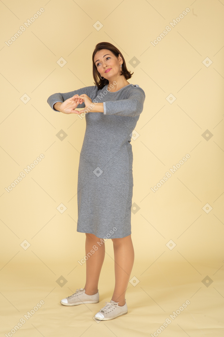 Side view of a woman in grey dress showing heart gesture