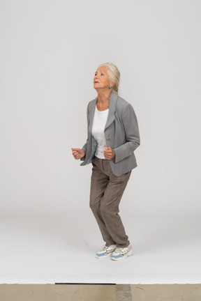 Side view of an old lady in suit jumping