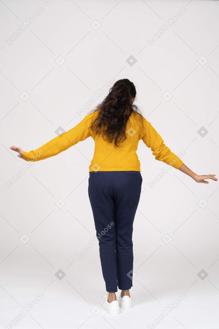 一个穿着休闲服的女孩张开双臂站立的后视图