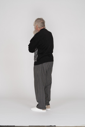 Rear view of elderly man standing with crossed arms