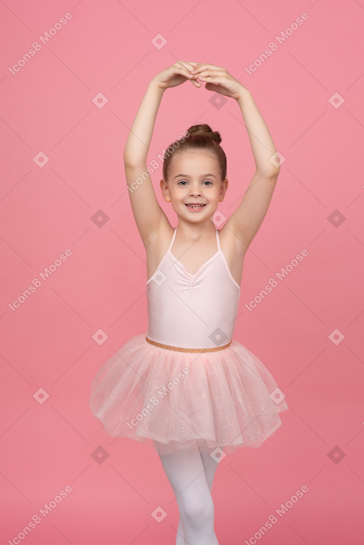 Bambina che indossa un tutù e in piedi in posizione di balletto
