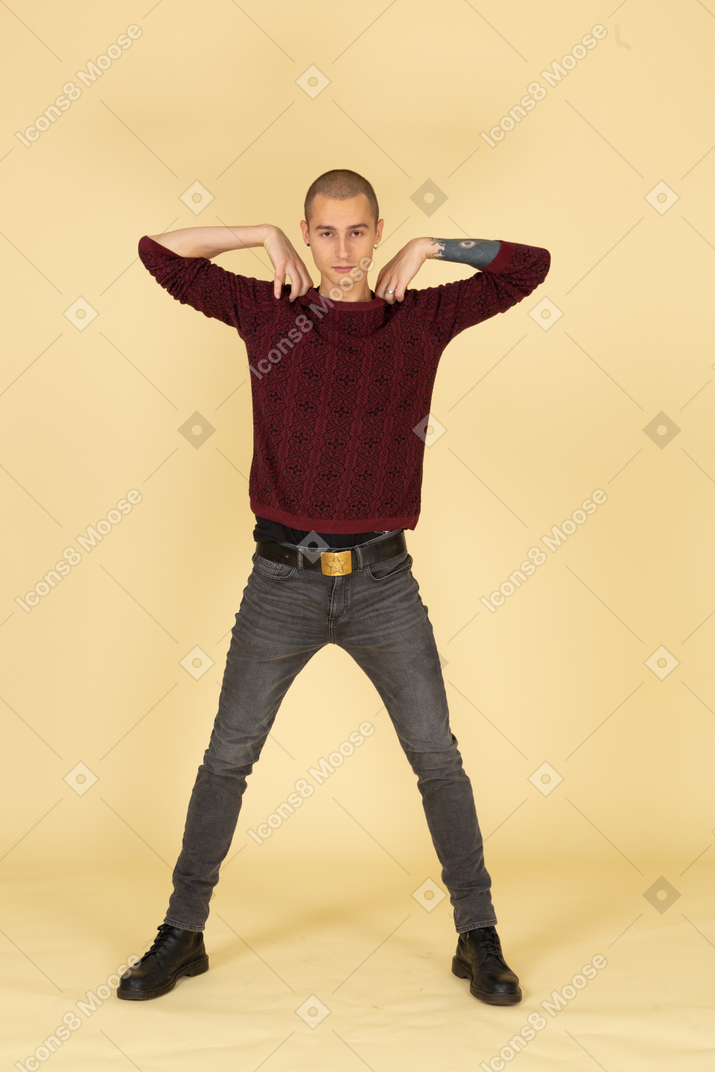 Vista frontale di un giovane uomo in pullover rosso toccando le spalle