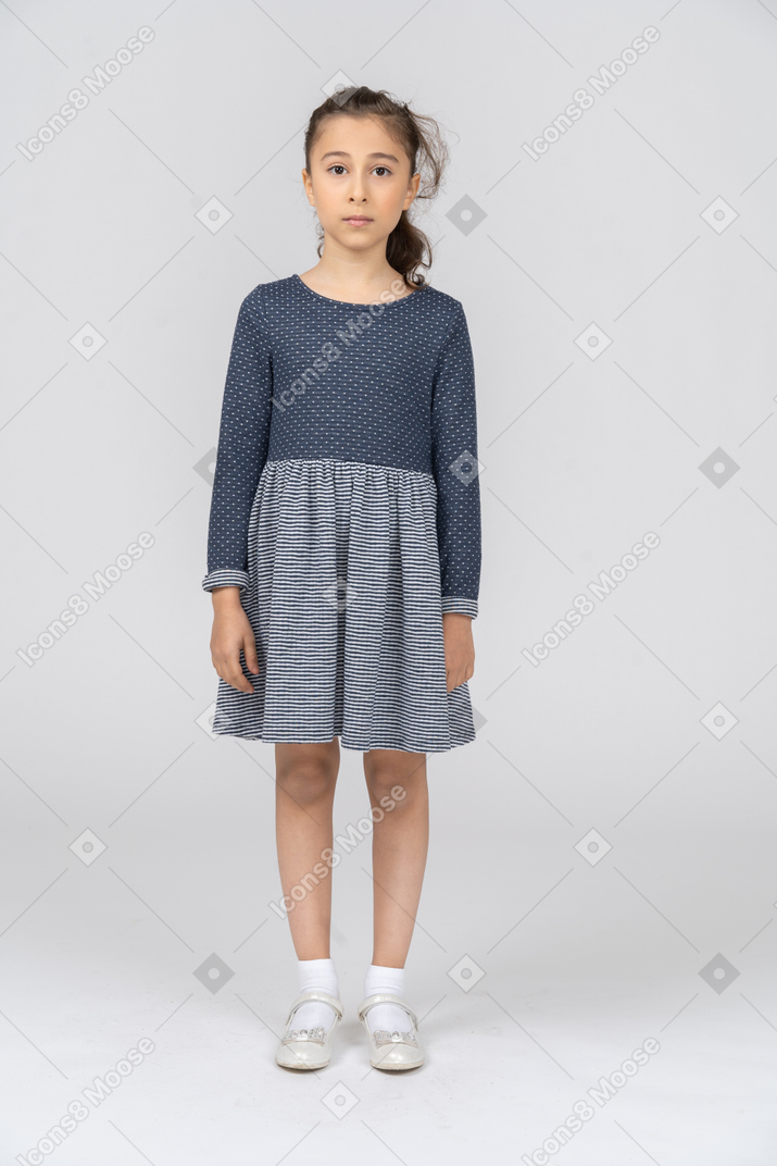Vue de face d'une fille en vêtements décontractés debout avec les bras sur les côtés