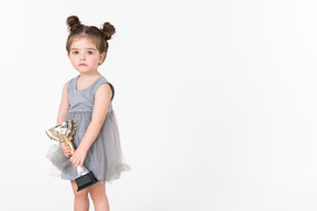 Niña sosteniendo una copa de premio