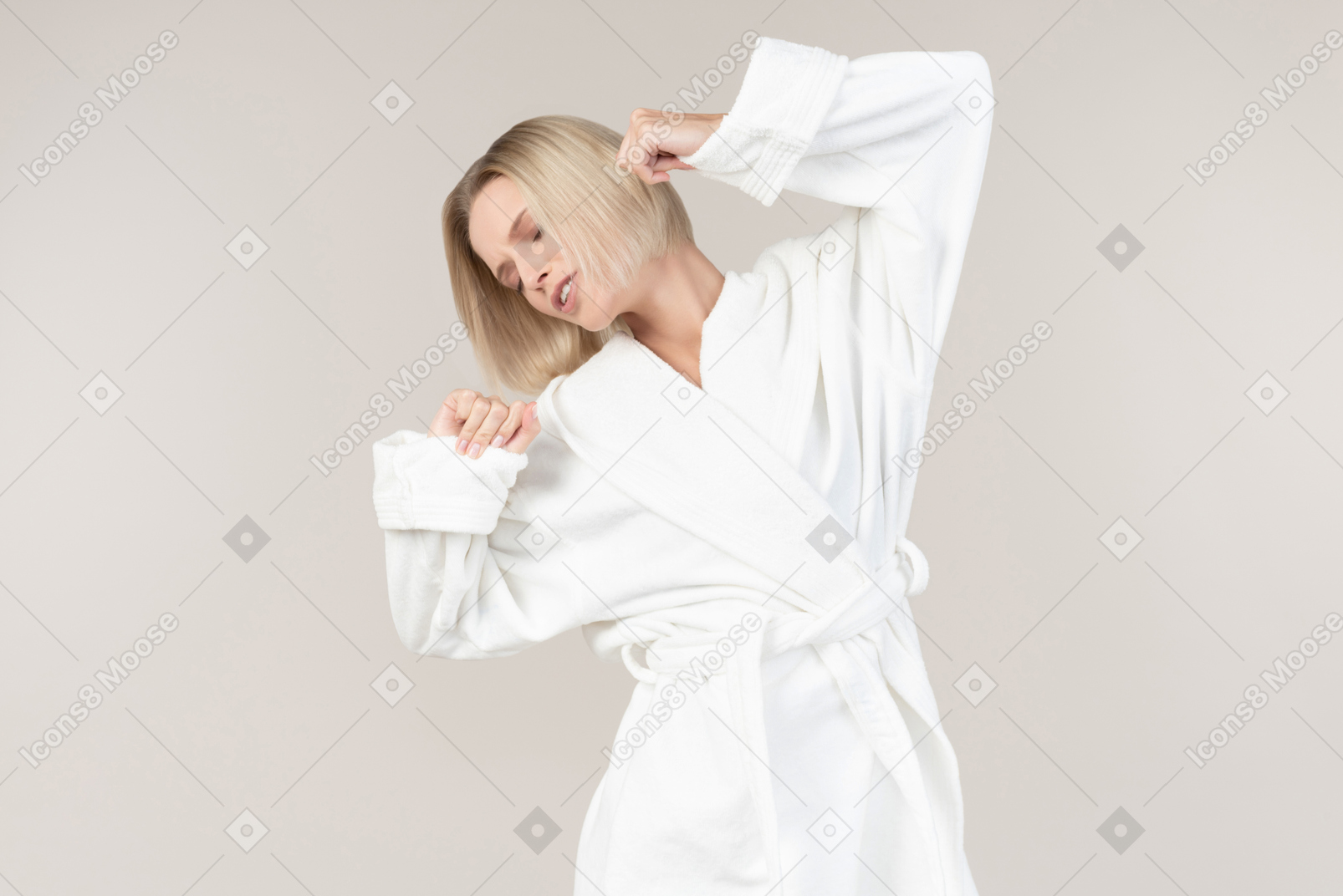 Young woman in bathrobe stretching her arms