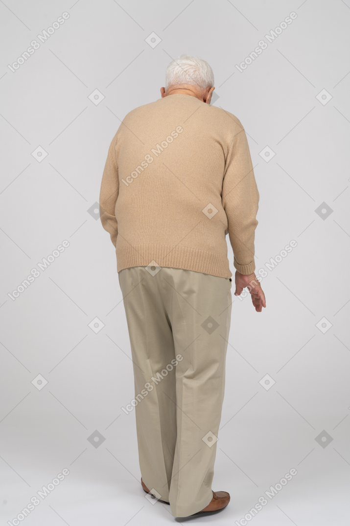 カジュアルな服を着て歩いている老人の背面図